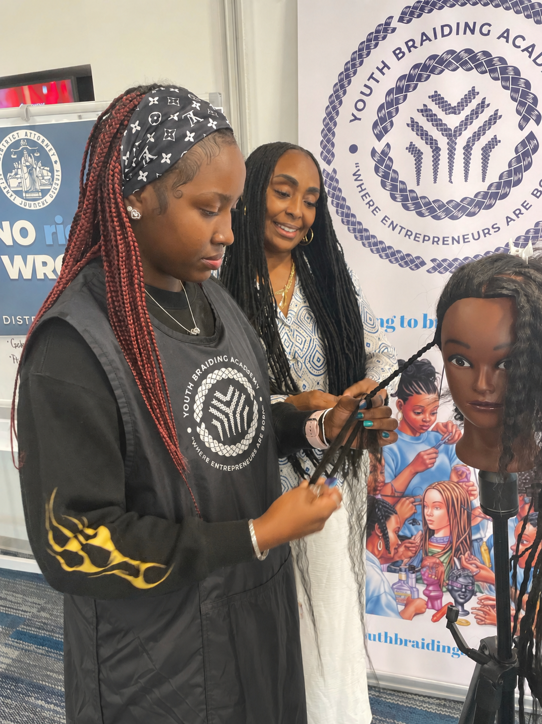 Dionne James teaching a student to braid